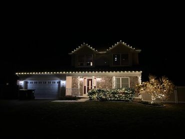 A house decorated with warm white Christmas lights at night.