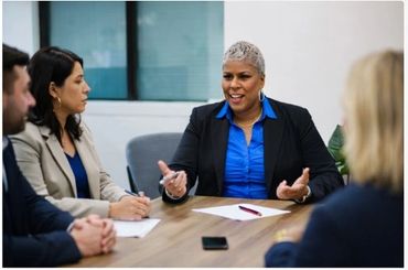 Business meeting with a confident woman speaking and others listening attentively.