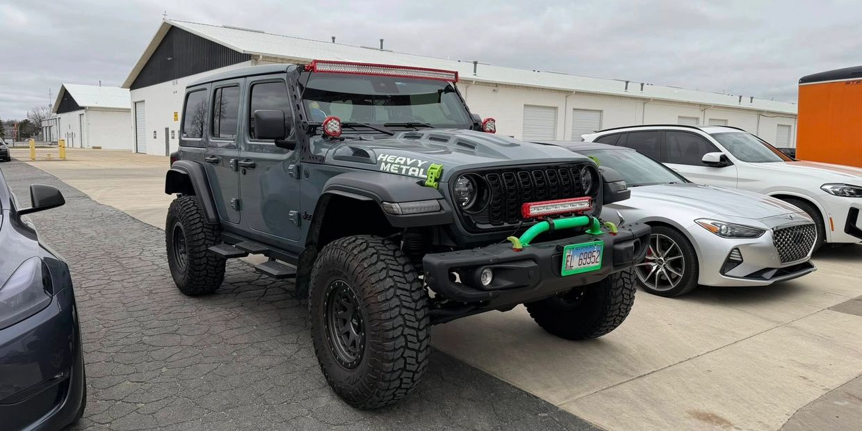 A rugged Jeep Wrangler with off-road modifications parked in a lot.