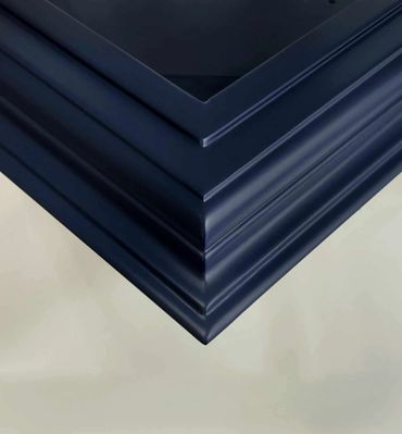 Close-up of a corner of a dark blue wooden frame with intricate molding.