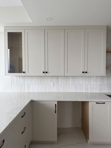Modern kitchen with sleek gray cabinets and white marble countertops.