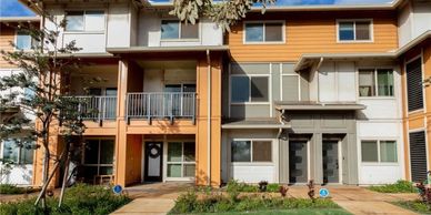 Modern townhouse complex with orange and gray exterior under a blue sky.