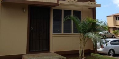 Exterior of a beige two-story house with a small porch and palm tree.