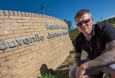 Man posing by Reaburn Centre Juvenile Justice Centre sign.