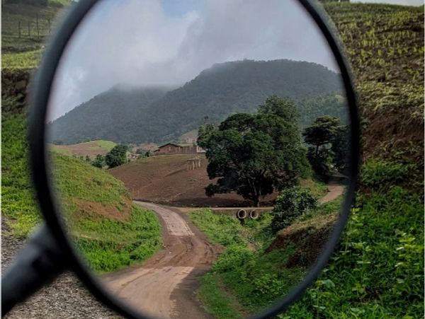 Camino de tierra en paisaje montañoso visto a través de un espejo.