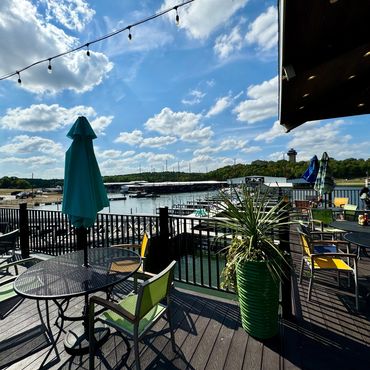 Outdoor seating area overlooking a marina on a sunny day.