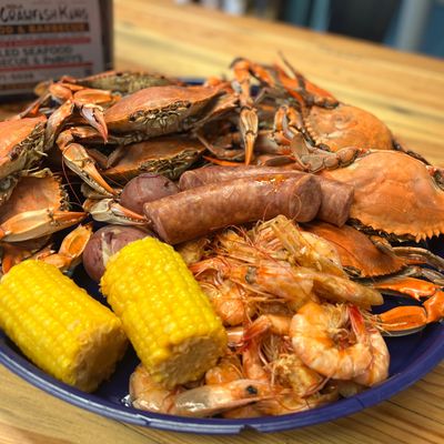 A seafood boil platter with crabs, shrimp, corn, sausage, and potatoes.
