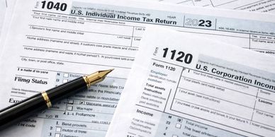 U.S. tax forms 1040 and 1120 with a fountain pen.