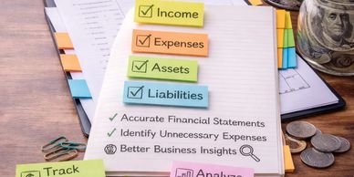 Checklist and notes on income, expenses, assets, liabilities, and financial tracking on a desk.