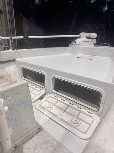 Open storage compartments on a white boat deck with a Watersnake trolling motor.