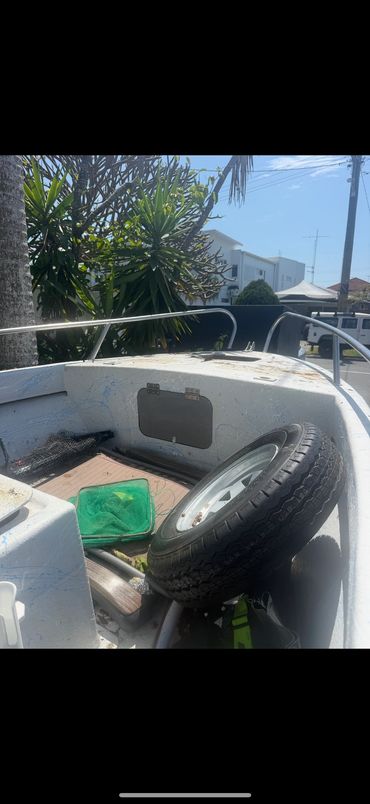 Boat interior with a spare tire and fishing net under sunlight.