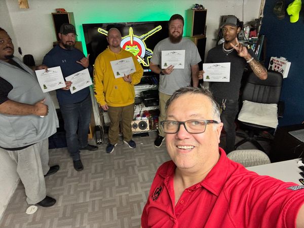 Group photo with certificates and a smiling man in red taking a selfie.