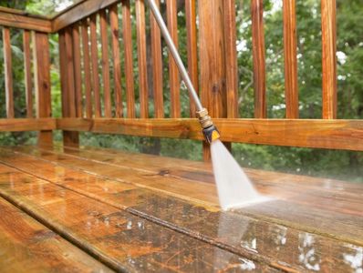 Pressure washing a wooden deck to clean it.