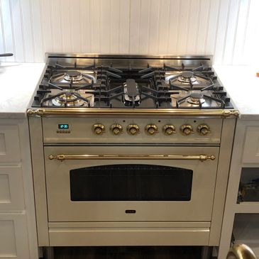 Elegant cream-colored gas stove with brass knobs and handle.