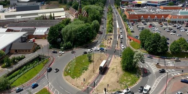 A roundabout with traffic and surrounding buildings in an urban area.