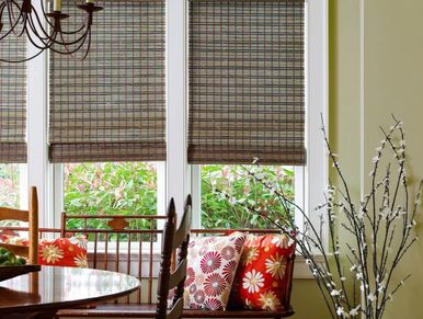 Cozy dining area with floral cushions and bamboo blinds on windows.