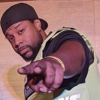 Man wearing a cap pointing towards the camera with a confident expression.