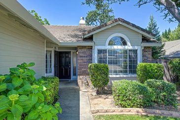 Front entrance of a suburban house with bushes and a large window.