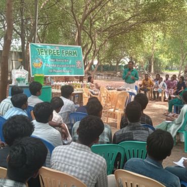 A group attends an outdoor seminar at Jeypee Farm under shaded trees.