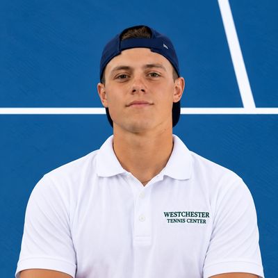 Young man in a white polo and blue cap on tennis court.