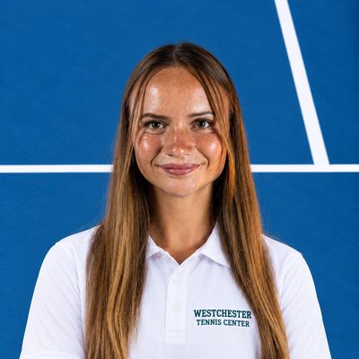 Woman wearing a Westchester Tennis Center polo shirt on a tennis court.