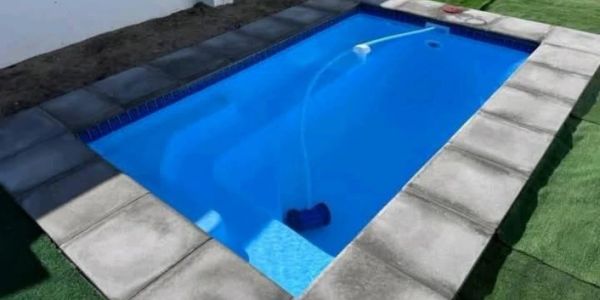 Small rectangular outdoor pool with blue water and stone border.