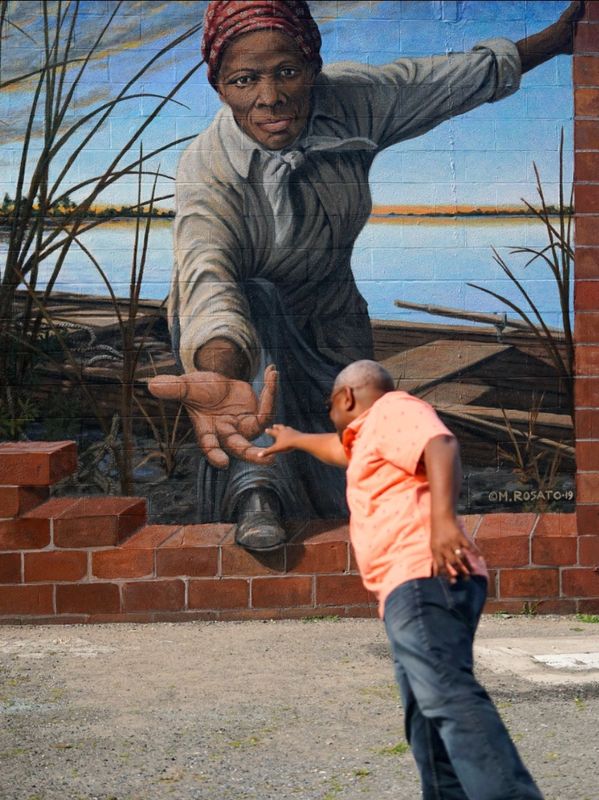 A man reaches out to a mural of a woman extending her hand.