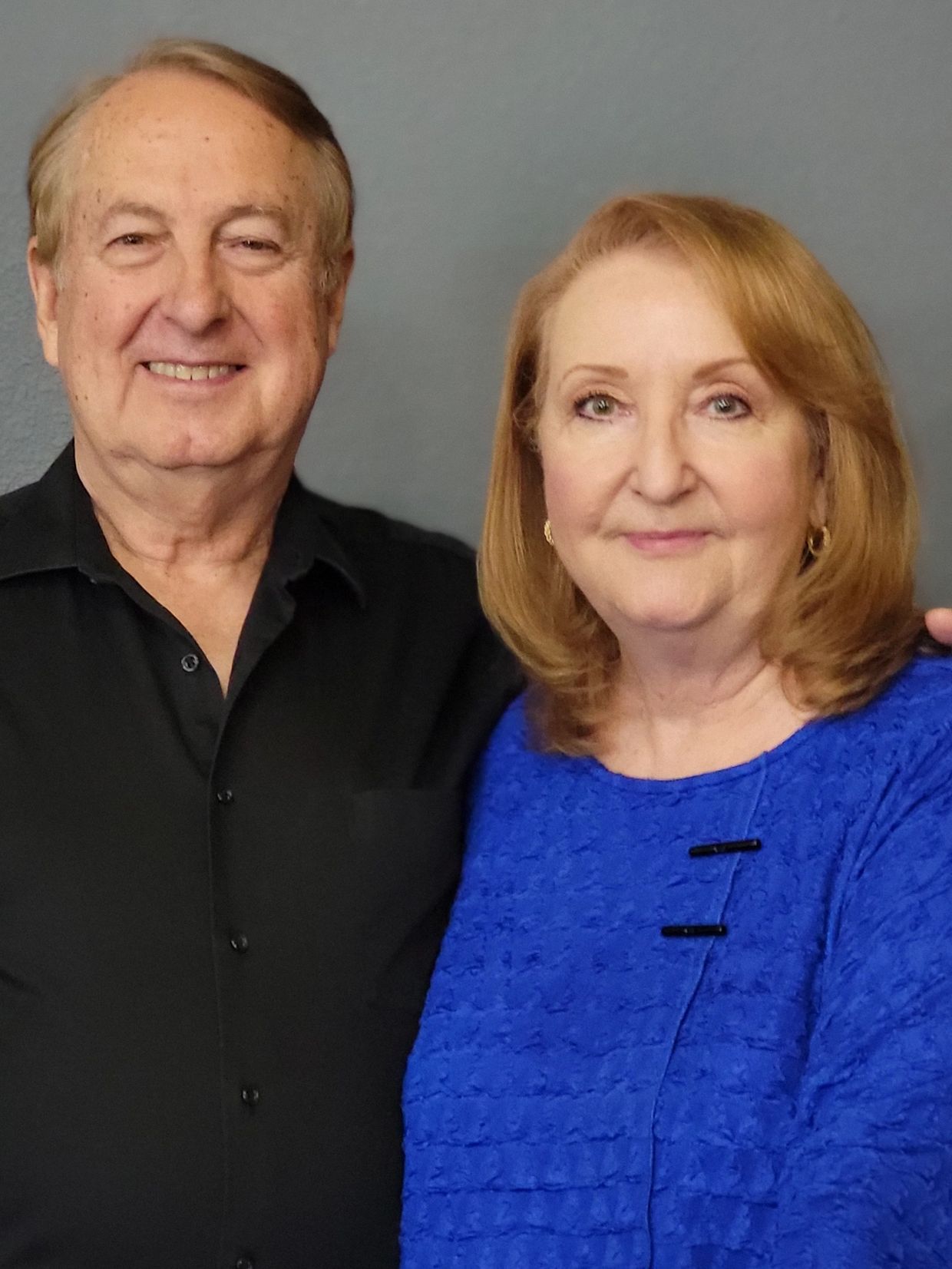Smiling older couple posing together against a plain background.