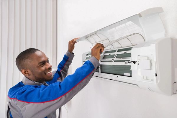 Happy Male Technician Checking Air Conditioner At Home