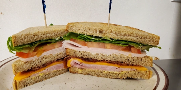 Two sandwich halves with turkey, ham, cheese, lettuce, and tomato.