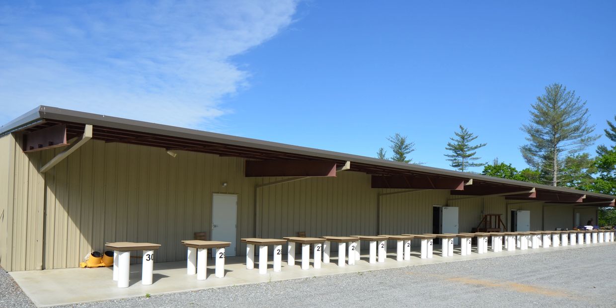 Club House with in-door bathrooms with 30 benches pointing down a 300-yard rifle range. 