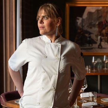Woman chef in white jacket looking away.