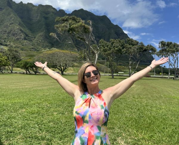 Woman with open arms in a sunny mountain park.