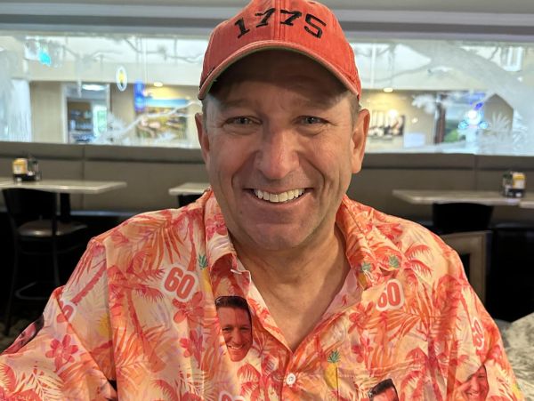Man smiling in a colorful shirt and red cap.