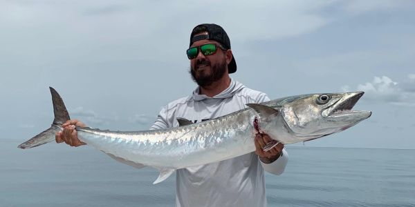 Man holding a large fish by the sea.