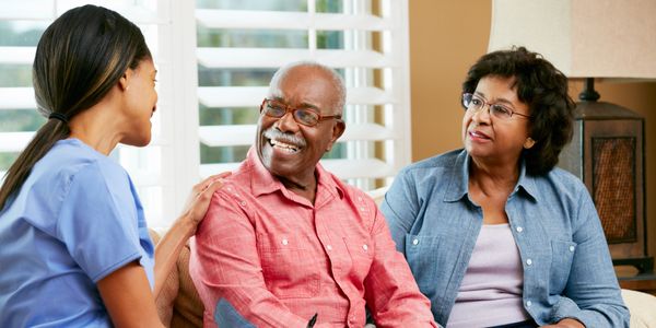 Nurse Making Notes During Home Visit With Senior Couple