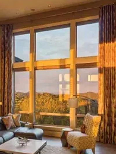 Cozy living room with large windows showcasing a scenic mountain view at sunset.