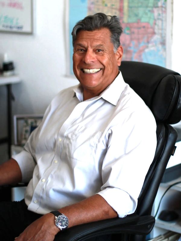 Smiling man in white shirt sitting on office chair.