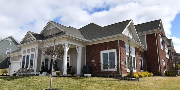 Modern brick house with white pillars and large windows.