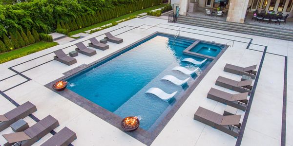 Custom vinyl pool & spa featuring natural stone coping , fire bowls and Patterned Concrete Patio