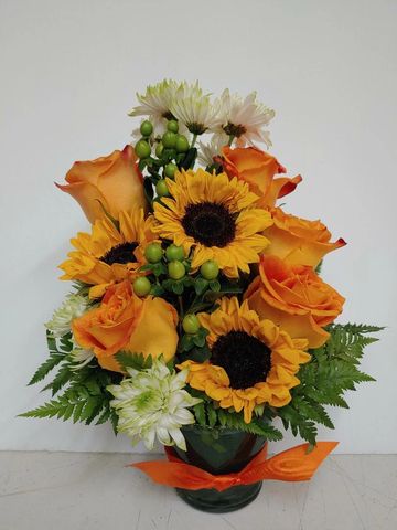 Beautiful sunflowers are added to bright orange roses to create this custom floral design.
