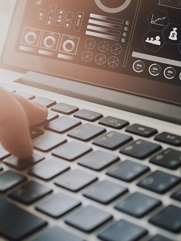 Finger typing on a laptop keyboard with analytics on screen.