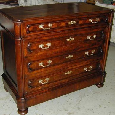 Antique wooden chest of drawers with ornate brass handles.