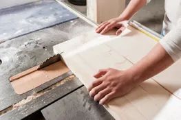Person cutting fabric with a rotary cutter on a table.