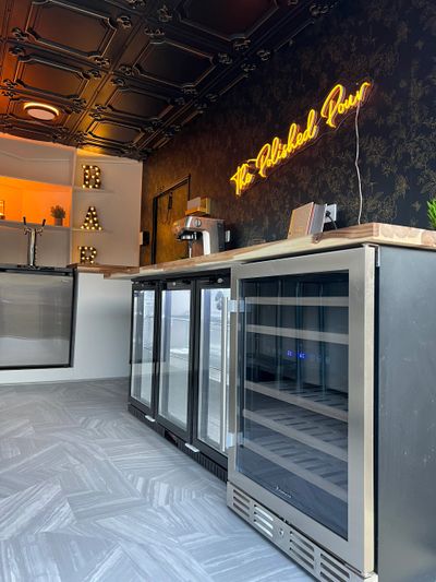 Modern bar area with wine coolers and neon sign.