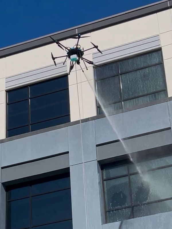 Drone spraying water on a building's window.