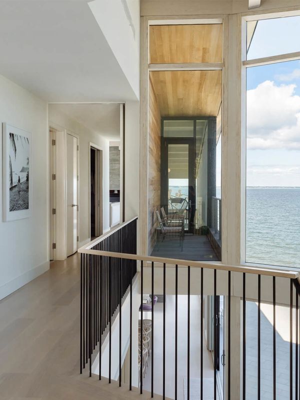 Modern hallway with glass balcony overlooking the ocean.