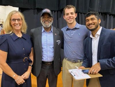 Four diverse people smiling and standing together indoors.