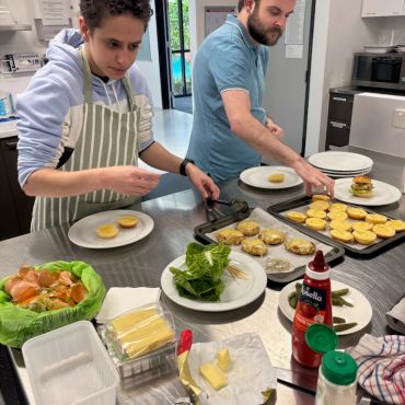 Two people assembling burgers in a kitchen.