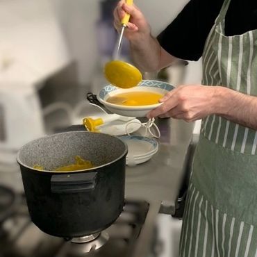 Person ladling soup into a bowl in the kitchen.